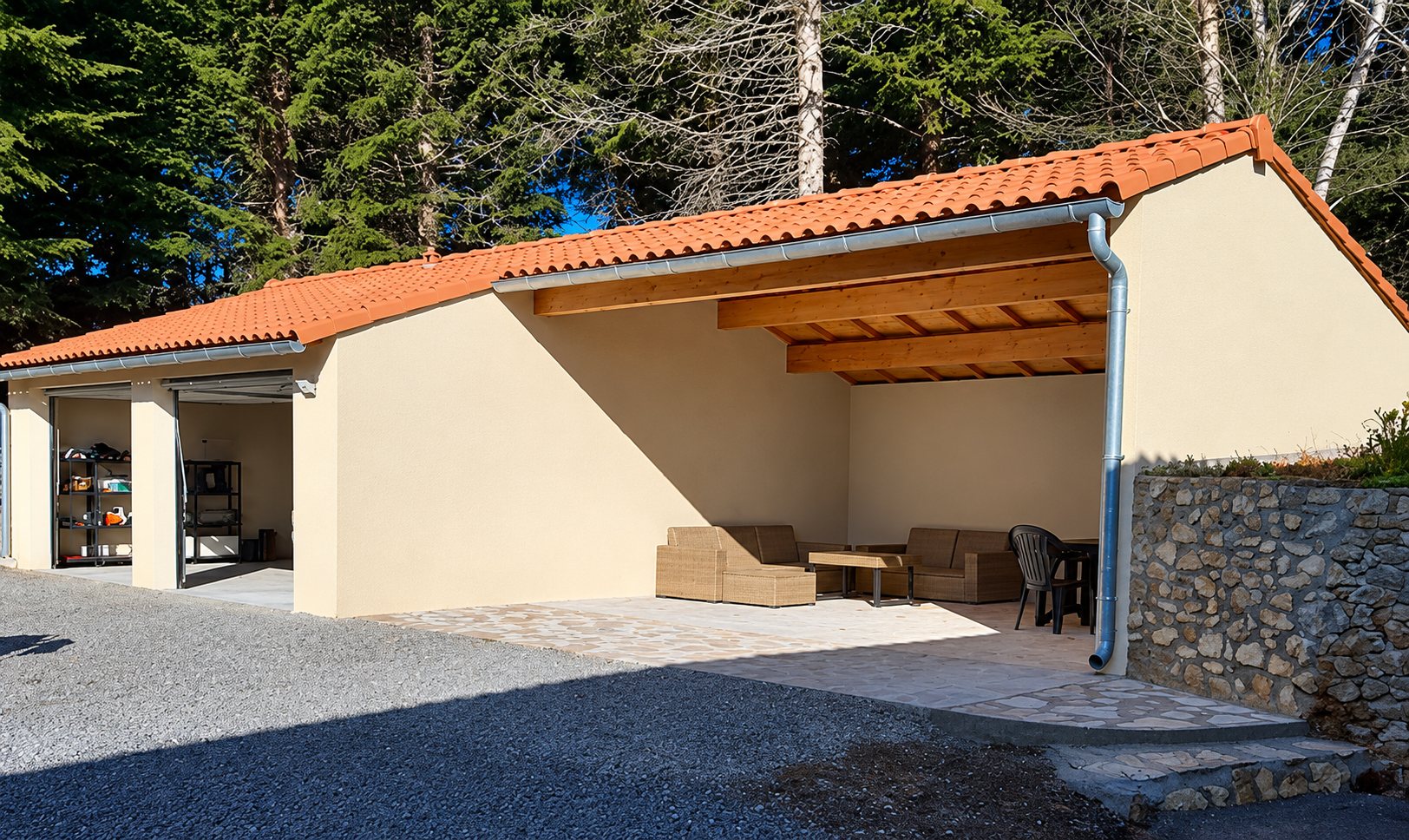 Bâtiment neuf à toit de tuiles avec une partie ouverte aménagée en salon de jardin